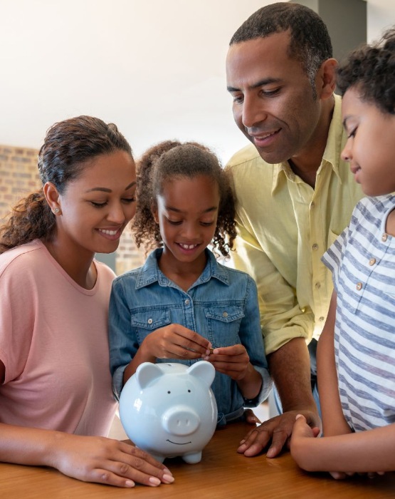 a family of four putting money in a piggy bank