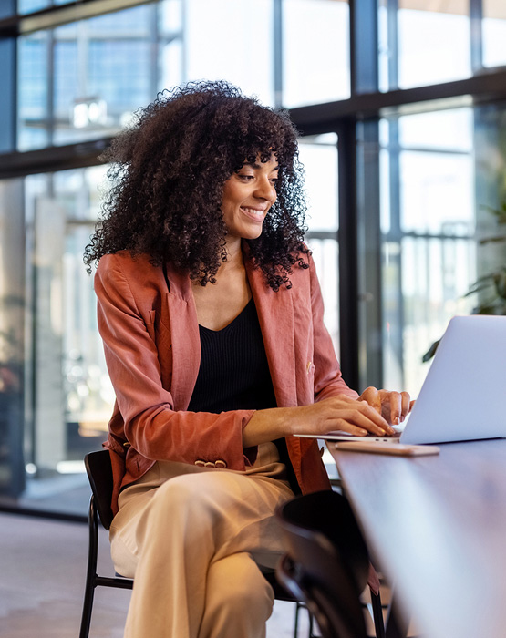 business woman sitting at desk looking at her laptop computer
