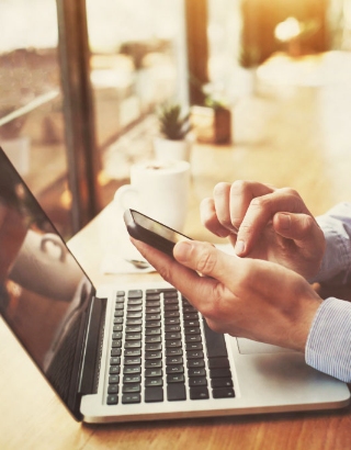 a person on their mobile phone and working on their laptop computer